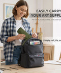 Woman placing 30 Slot Roll Up Paint Brush Holder, Premium Canvas Brush Organizer For Artists, Army Green into backpack