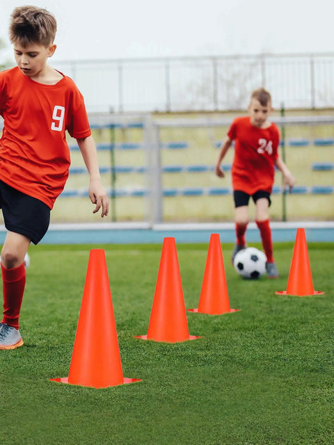 Two boys practicing soccer with 24 Piece 12 Inch Traffic Cone Set, Plastic Construction Safety Cones For Parking Lot, Sports Training, Orange.