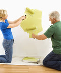 Couple painting wall on floor protected by Heavy Duty 12oz Cotton Duck Canvas Drop Cloth 20x20 Ft Washable And Reusable Floor Protector