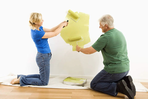 Couple painting wall on floor protected by Heavy Duty 12oz Cotton Duck Canvas Drop Cloth 20x20 Ft Washable And Reusable Floor Protector