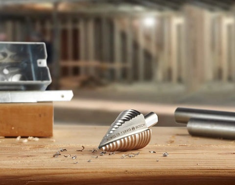 Close-up of Turbo Step Drill Bit Set For Cordless Drills, high speed steel bit on wooden surface with metal shavings