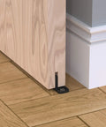 Sliding Barn Door Floor Guides Black 4 Pack Bottom Track Guides For All Sliding Doors Including Bypass And Pocket Doors Easy To Install Closet And Barn Style Durable Plastic Guides For Grooved And Non Grooved Tracks installed on wooden floor