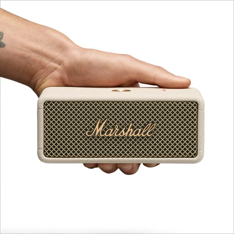 Hand holding Emberton III Portable Bluetooth Speaker With Rugged Waterproof Build And Dust Proof Design Loud Stereo Sound And Deep Bass For Travel Outdoors And Everyday Use Compact Wireless Cream, front view