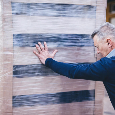 Man packing boxes with Heavy Duty Clear Cast Stretch Wrap 80 Gauge 19.7 X 6000 Ft Roll for shipping.