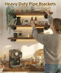 Woman installing Industrial Black Iron Pipe Shelf Brackets Wall Mount DIY Shelving with decor, kitchen counter visible