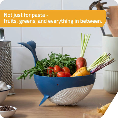 Pastail Medium Whale Shaped Pasta Colander for draining pasta, vegetables, and fruit on countertop with produce inside