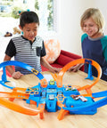 Children playing with Hot Wheels Criss Cross Crash Track Set With 1 To 64 Scale Car Four Intersections Motorized Booster Power Epic High Speed Crashes And Car Feeder Ramp Amazon Exclusive Toy For Kids on table.