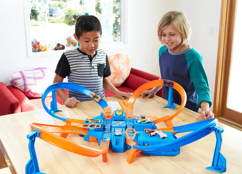 Children playing with Hot Wheels Criss Cross Crash Track Set With 1 To 64 Scale Car Four Intersections Motorized Booster Power Epic High Speed Crashes And Car Feeder Ramp Amazon Exclusive Toy For Kids on table.