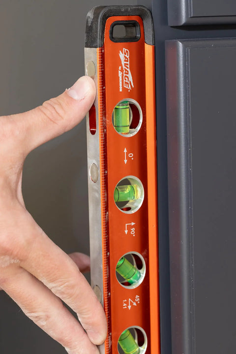 Savage Grip 11-Inch Aluminum Torpedo Level With Brightview Technology and four neodymium magnets in use against a wall.