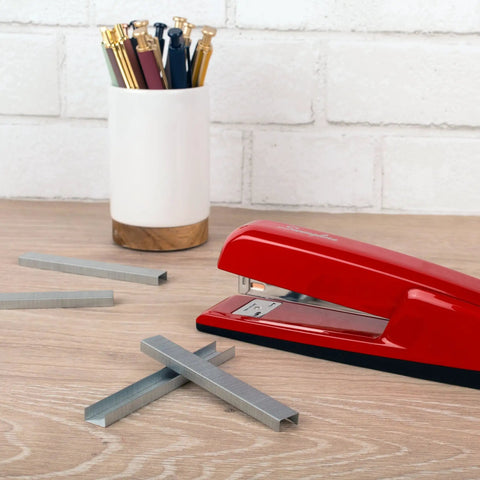 Premium One Quarter Inch Staples, 210 Per Strip, Five Pack, scattered on desk with stapler and pen holder