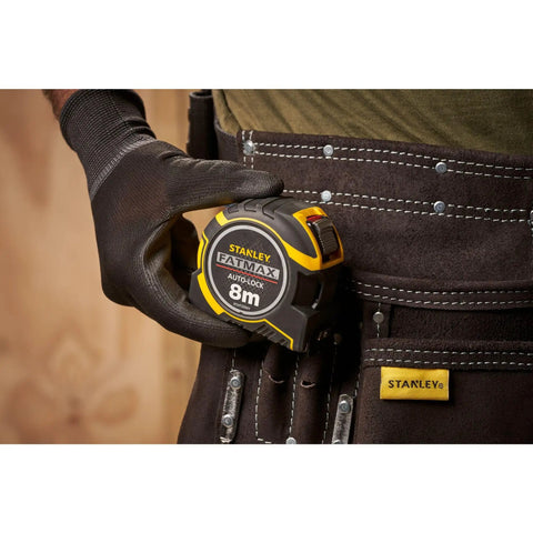 Gloved hand holding Fatmax Autolock Tape Measure 8m Metric Only Yellow Black, Reverse Lock For One-Handed Control, in tool belt.