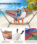 Heavy Duty 550 Lbs Double Hammock With Stand Included And Portable Carrying Bag For Outdoors And Indoors Rainbow Stripe Upgraded 2 Person Hammock With Frame displayed on tropical beach.