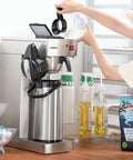 Person operating Commercial Airpot Coffee Brewer With 2.2L 74oz Thermal Carafe Stainless Steel Pour Over Coffee Machine 24 Hour Heat 120V 1450W Dispenser For Cafe Restaurant Cafeteria