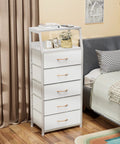 Five Drawer White Dresser With Wood Top And Steel Frame, Vertical Fabric Storage Tower beside a bed in a modern bedroom setting