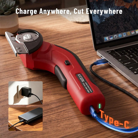 Katerk 4.4V Cordless Electric Scissors & Cardboard Cutter With 2pcs Blades charging via USB-C next to a laptop on a wooden surface.