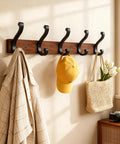 Solid Wood Wall Mounted Coat Rack With Five Heavy Duty Metal Hooks Holds Up To 25 Lbs Each For Hats Coats Towels Backpacks And Keys In The Closet Entryway Bedroom Or Bathroom 2 Pack displaying various items hanging in a sunlit room.