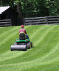 Person using Heavy Duty Tow Behind Poly Lawn Roller 42 Gallon 390 Pound Capacity with 18 by 36 Drum in large yard