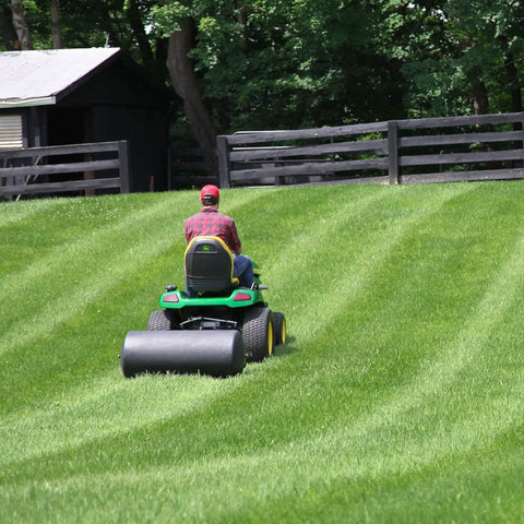 Person using Heavy Duty Tow Behind Poly Lawn Roller 42 Gallon 390 Pound Capacity with 18 by 36 Drum in large yard