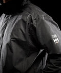 Close-up of black Men's Waterproof Shell Jacket With Detachable Hood And High Collar, Breathable Fully Taped Seams, no shoulder seams.