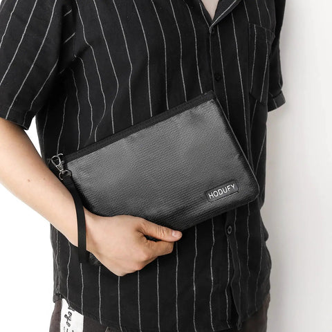 Man holding Extreme Heat Fireproof Money And Document Bag 2000F, Zippered A5 Safe Cash Pouch With Strap, black color.