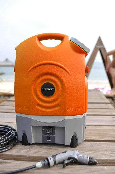 On The Go Portable Spray Washer With Built In Water Tank, showing orange tank, black hose, on wooden deck by beach