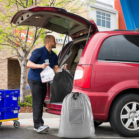 Man loading car with 2 Pack Travel Laundry Bags With Handles And Aluminum Carabiner Dirty Clothes Organizer in red vehicle trunk.