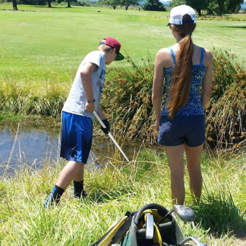 Man using 18 Foot Telescopic Golf Ball Retriever With Lightweight Aluminum Shaft Stainless Cup And Locking Hinged Design For Easy Water Pond Mud And Rough Retrieval No Fuss Pickups Every Time beside a pond on a golf course.