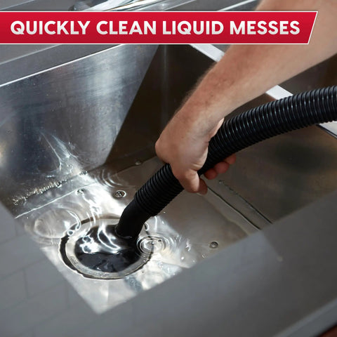 Hand using a hose from Premium 5 Gallon Wet Dry Shop Vac With Badass 135 Air Watt Suction to clean liquid messes in a stainless steel sink.