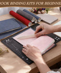 Person using bone folder on pink A5 paper from All In One 145Pcs Book Binding Kit For Beginners With A5 Paper And Tools
