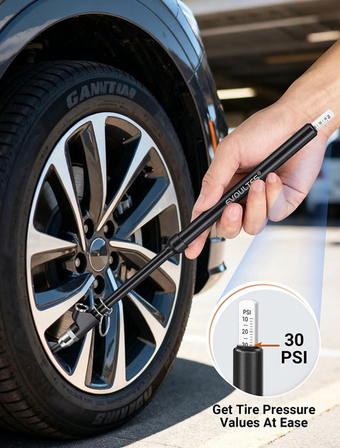 Tire pressure gauge, hand-held black with extended tube, side view beside a car tire.