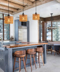 Total Vibe Hand Woven Rattan Pendant Light above kitchen island with wood bar stools, farmhouse decor and natural lighting.