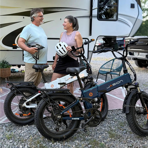 Two people standing beside Beast 1400W Peak Electric Bike for Adults with Full Suspension and Fat Tires near an RV.