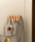 Foldable Wall Coat Rack With Five Hidden Hooks, modern wooden wall mount holding a bag and coat in a narrow hallway.