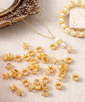Gold Mini Crown Charms 100 Pieces, 3D Vintage Alloy Queen King Crowns Beads With Large Hole scattered near a bracelet and pearls