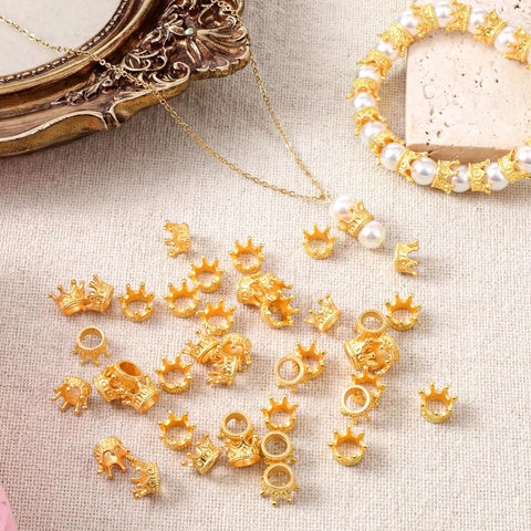 Gold Mini Crown Charms 100 Pieces, 3D Vintage Alloy Queen King Crowns Beads With Large Hole scattered near a bracelet and pearls