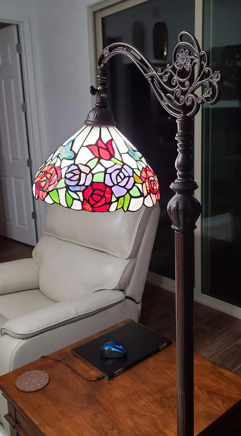 Tiffany Inspired Arched Stained Glass Floor Lamp 62 Inches Tall With rose pattern shade in cozy living room next to chair and table.