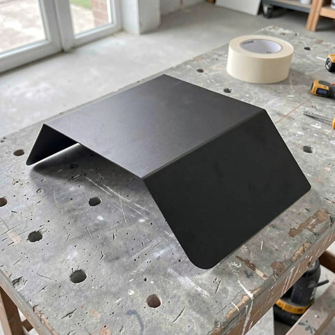 Heavy Duty Aluminum Wall Mount EV Charging Station Rain Shield Weatherproof Canopy on a workbench, showcasing black finish.