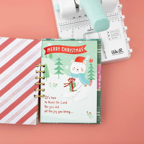 Mini Cinch Binding Tool For DIY Books And Notebooks With Wire Or Spiral Coils Pro Grade Mini Binding Machine next to a Christmas-themed notebook