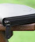 Close-up of the Glove Caddie Wallet for Golfers, showing sleek black exterior and durable zipper on a wooden surface.