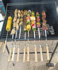 22 Inch Stainless Steel Flat Kabob Skewers With Wooden Handles 12 Pack Reusable Shish Kebab Sticks For Meat Shrimp Chicken Vegetables And Sausage Heavy Duty BBQ Grill Skewers displayed on a grill with mixed foods.
