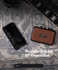 Ultra Portable 5W Dual Speaker Bluetooth Guitar Amplifier with Rechargeable Battery beside guitar and smartphone on rug.