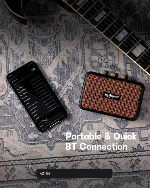 Ultra Portable 5W Dual Speaker Bluetooth Guitar Amplifier with Rechargeable Battery beside guitar and smartphone on rug.