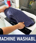 Person placing a 7-Pack Heavy Duty Padded Moving Blanket in a washing machine, demonstrating machine washable feature.