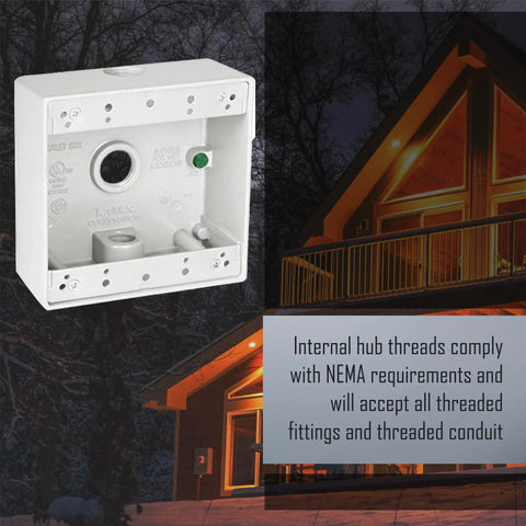 Two Gang White Weatherproof Junction Box Four Point Five By Four Point Five Inch Two Inch Deep With Three Half Inch Threaded Holes Beefy Die Cast Metal Construction Powder Coated Finish Outdoor Electrical Box For Outlets And Branch Circuit Wiring next to a cabin.