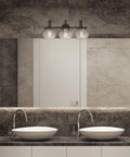 Lofty Chic Three Light Vanity Light In Dark Bronze With Clear Glass Shades And Antique Brass Accents in modern bathroom
