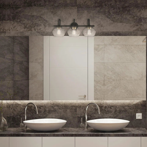 Lofty Chic Three Light Vanity Light In Dark Bronze With Clear Glass Shades And Antique Brass Accents in modern bathroom