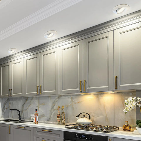 Big Time Brightness Rotatable Led Retrofit Downlight Gimbal illuminating modern kitchen cabinetry with gold accents.