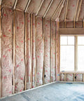 Pro Grade R13 Kraft Fiberglass Roll Insulation Real Deal For 2x4 Walls installed between studs in a room.