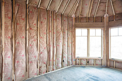 Pro Grade R13 Kraft Fiberglass Roll Insulation Real Deal For 2x4 Walls installed between studs in a room.