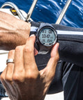 Person adjusting wrist-worn scuba and freediving dive computer with logbook display, Get Your Hands On This Awesome Scuba And Freediving Dive Computer That Comes Packed With A Handy Dive Logbook Smart Dive Planner Essential Safety Alarms And Heart Rate Monitoring To Keep You Safe And Stylish On Every Dive.